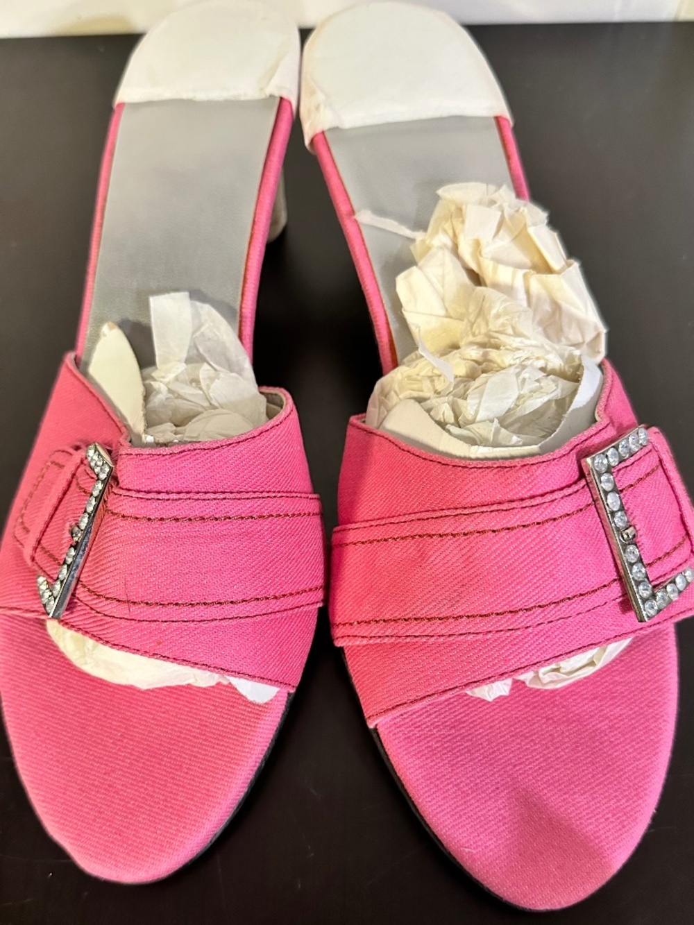 These are a pair of pink denim heels with a leather outsole, rhinestone buckle.